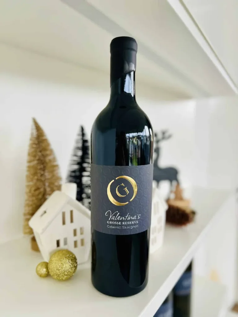 Eine dunkle Glasflasche GILG Valentinas Große Reserve mit schwarzem Etikett und silbernem Text, gekrönt von einem versiegelten schwarzen Verschluss.