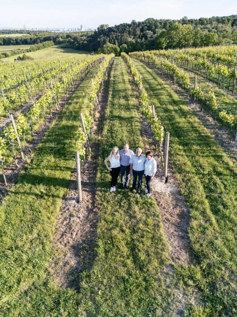 Familie GILG steht gemeinsam zwischen Weinstöcken im Weingarten bei Hagenbrunn